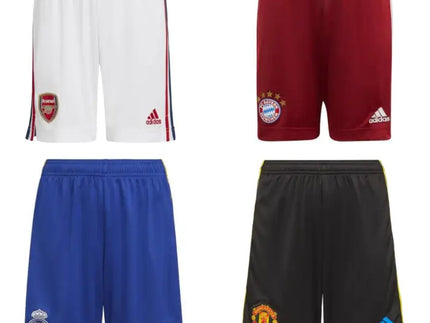 Quattro pantaloncini calcio adidas in bianco, rosso, blu e nero con loghi squadra e branding visibile.