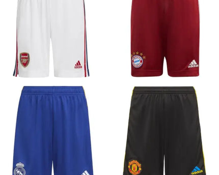 Quattro pantaloncini calcio adidas in bianco, rosso, blu e nero con loghi squadra e branding visibile.