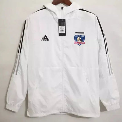Giacca bianca colo-colo 2022 23 adidas con strisce nere sulle maniche e stemma colo-colo blu e rosso sul petto
