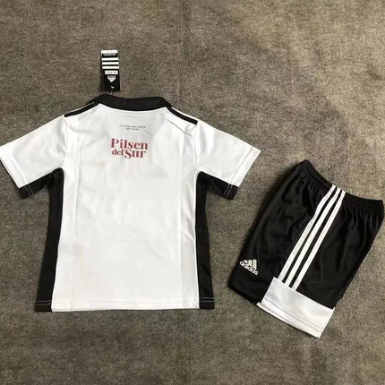 Vista posteriore del kit adidas calcio giovanile maglia bimbo colo-colo home 2022 23 bianca e nera con testo rosso pilsen del sur