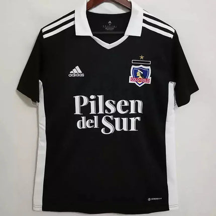 Maglia colo-colo trasferta 2022 23 adidas nera con colletto bianco strisce sulle maniche pannelli laterali e stemma club