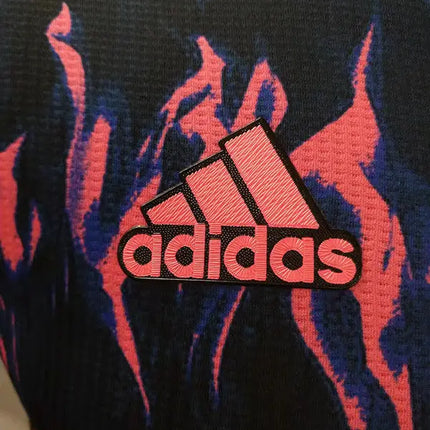 Maglia manchester united pre-match 2022/23 in tessuto tecnico con logo adidas ricamato rosa su motivo fiamme blu e nero