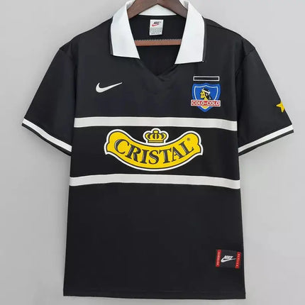 Maglia retro colo-colo trasferta 1996/97 nera con colletto bianco, bande orizzontali e logo sponsor cristall giallo